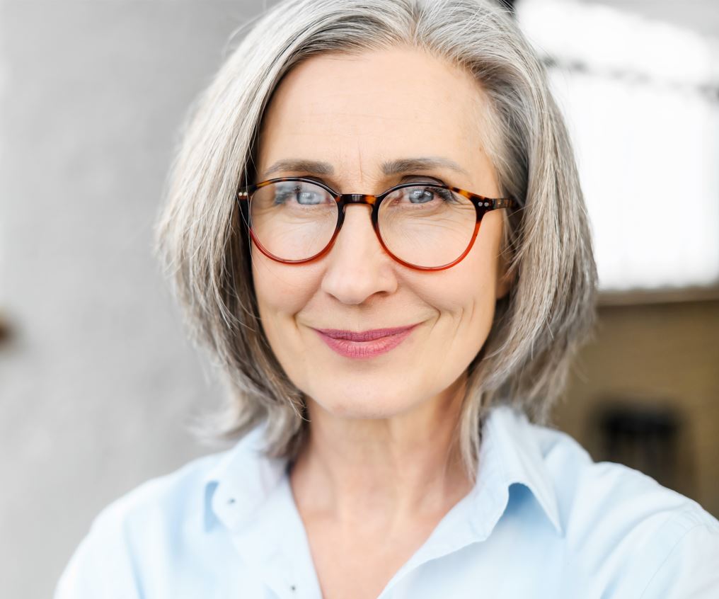 Woman smiling with grey hair and glasses